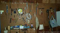 Wide view showing pegboard with various hung hand tools like hammers, pliers, screwdrivers, and a tote bag for clothes pins