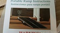 Instruction manual showing the portable ramp setup over stairs for wheelchair use.
