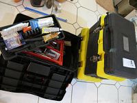 Photo showing three plastic tool boxes stacked; black, yellow, and another black box.