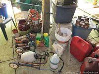 Photo showing garden cart, gas cans, sprayer, buckets, rope, garden tools, and planters clustered together.