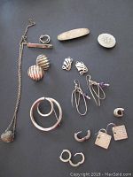 Photo showing entire lot on black background including necklace, several pairs of earrings, and pins.