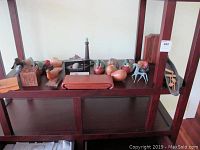 Wooden duck figures, carved wooden cube, Cocobolo box, model lighthouse, and metal horse figurine displayed on wooden shelf