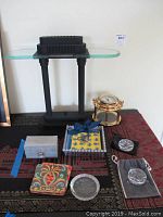 Photo showing black table lamp with glass top along with Seth Thomas clock, coasters, and other items on tabletop
