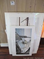 Three stacked prints leaning against a wall, showing edges and sizes