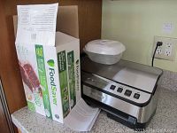 Photo showing the FoodSaver vacuum sealer unit and the original box of bags on a kitchen countertop.
