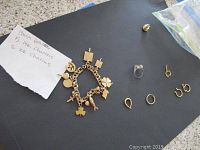 All items laid out on black background: bracelet with charms, ring, stud earring, four hoop connectors