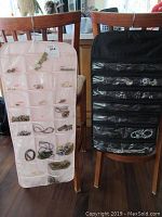 Two hanging pocket jewelry organizers on chairs filled with assorted costume jewelry