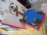 Roku 3 model 4200X on top of its box, partially covered with blue painter's tape, sitting beside a Maryland-themed carrying bag.