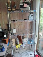 Full view of the Nexel wire metal shelving unit in a room showing contents removed from shelving but with some items around it for scale.