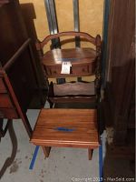 Full view of wooden sewing stand with drawer and magazine rack behind a rectangular wooden stool