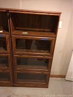 Full view of the front of the wooden barrister bookshelf with three glass door compartments and an open top shelf.