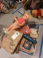 Mattel Chatty Cathy doll wrapped in plastic sitting next to vintage Vogue dolls box and blue rotary toy phone with vintage items