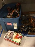 Blue plastic bin with multiple Hungarian dolls, wood carvings, souvenirs, and miscellaneous items. Box with souvenir items in front.