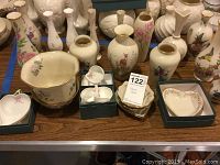 Overview of a collection of Lenox floral pattern vases and bowls arranged on a table with some pieces in original boxes, showing floral and deer designs.
