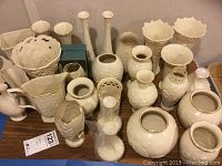 View of entire collection of Lenox ivory and gold porcelain vases and pitchers on wooden table