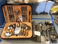 Set of silver-plated flatware and serving pieces in a tan-lined case and loose pieces with cloth wraps.