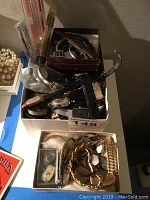 Photo showing boxes filled with various wristwatches, leather watch straps, and loose watch parts including some metal bracelets.