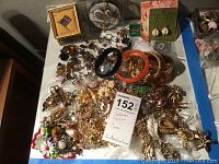 Top view of assorted costume jewelry including bangles, pins, earrings, and brooches on table.
