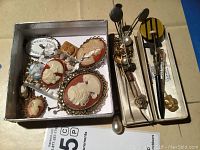 Overview of lot showing box of cameo brooches and tray of stick pins