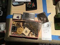 Full lot of military pins, medals, and a plaque. Items shown in a box and loose on a table with some small containers.