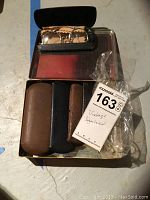 Photo showing three spectacles cases with a pair of rimmed spectacles in one case inside a box labeled with lot information.