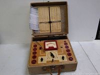 Front view of the Stark Model 9 55 tube tester with multiple tube sockets, analog meter gauge, control knobs, and case with lid open showing chart.