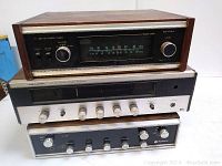 Three stacked vintage audio components including Electra ST7700 AM/FM stereo tuner on top, Realistic STA-15 receiver in the middle, and Nivico receiver at the bottom. Shows front control panels and knobs with wood trim.