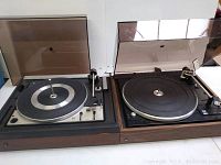 Pair of vintage Dual turntables side by side with dust covers, showing overall condition and presence of damage on one cover