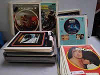 Stacked video discs placed on top of video disc player, showcasing titles like Excalibur, Rocky, and others