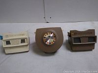 Three vintage Viewmaster viewers displayed side by side on a white surface.