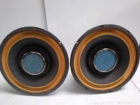 Front view showing speaker drivers with black cones, yellow surrounds, and blue center caps.