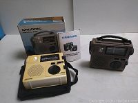 Photo showing two Grundig FR-200 radios, one beige with box and booklet and one grey, positioned on a flat surface.