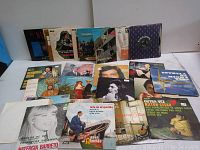Assorted vinyl records spread out showing album covers and sleeves, featuring various artists and musical genres.