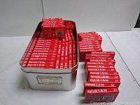 Metal bin filled with red and white Maxell UR90 tape boxes and additional stacks alongside