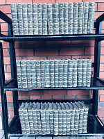 Three shelves containing 38 volumes of the Waverley Novels, spines facing forward showing ornate gilded designs and titles.
