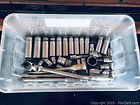 Plastic bin containing assortment of deep and shallow sockets, extension bars, adapters and universal joint
