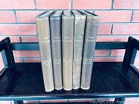 Five hardcover volumes of The Studio magazine, standing upright on a black cart, showing spines with dates and volume numbers.