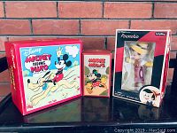 Three Disney toys displayed in original boxes: Mickey Riding Pluto, Minnie Mouse, and Pinocchio.