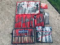 All tools laid out on concrete: hex keys, punch sets, chisels, ignition kit, disc