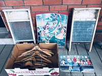 Two wooden washboards, one branded 'Royal Globe', two metal advertising signs, and a box of wooden advertising hangers displayed against a brick wall