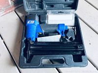 Campbell Hausfeld air nailer inside its molded plastic carrying case with box of air nails.