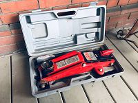 Red hydraulic trolley jack stored inside the original gray molded carrying case. Case has compartments shaped to fit the jack and handle.