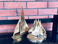 Single brass sailboat sculpture with smooth, minimalist design and two sails