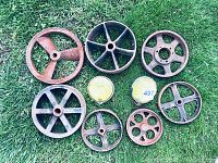 Top-down view of all cast iron gears and wheels plus two yellow reflectors laid flat on grass.