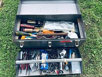 Overview of top section of toolbox showing screwdrivers, chisels, wood handled tool, and plastic bags with miscellaneous small items.