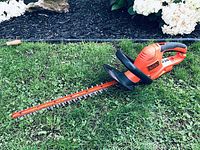 Full view of the Black and Decker electric hedge trimmer lying on grass, showing overall condition and design.