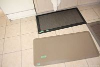 Two photos showing black, beige, and brown anti-fatigue kitchen mats in front of kitchen cabinets and floor tiles.