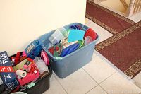 Two large plastic bins filled with assorted kitchen items including containers, cutting boards, and other small tools.