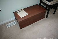 Ikea laminated storage chest with sliding top on rails, dark wood finish, rectangular shape. Size shown on MaxSold listing.