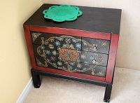 Photo of decorative East Asian wooden chest with 9 drawers and green felt pad on top.